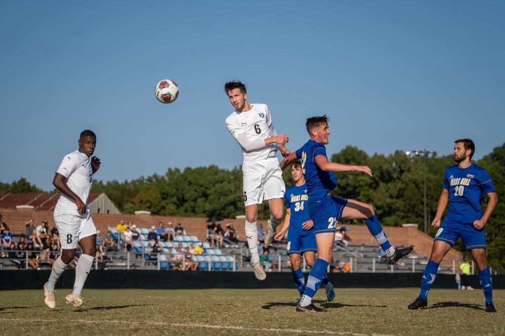College soccer player rising to win a header during a match